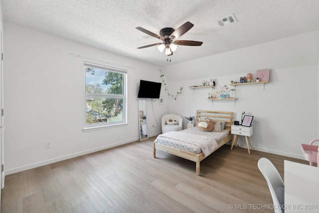 bedroom with a textured ceiling, light hardwood / wood-style flooring, and ceiling fan