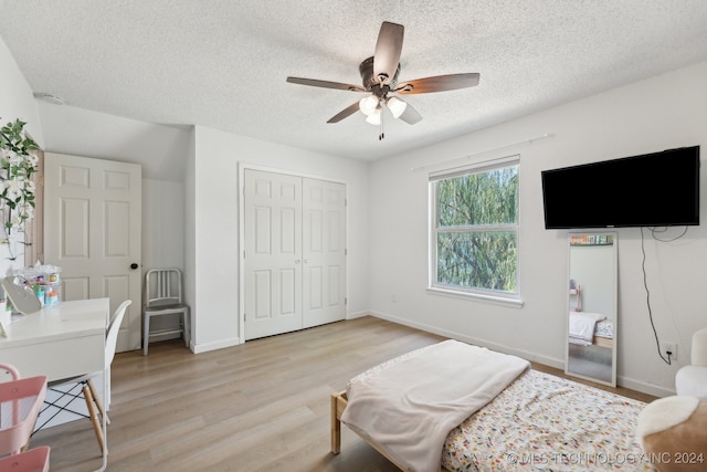 bedroom featuring light hardwood / wood-style floors, a closet, a textured ceiling, and ceiling fan