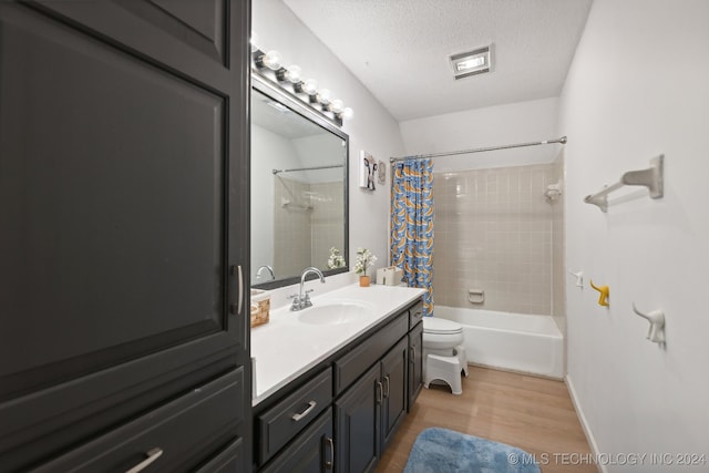 full bathroom featuring vanity, hardwood / wood-style flooring, shower / bath combo with shower curtain, toilet, and a textured ceiling