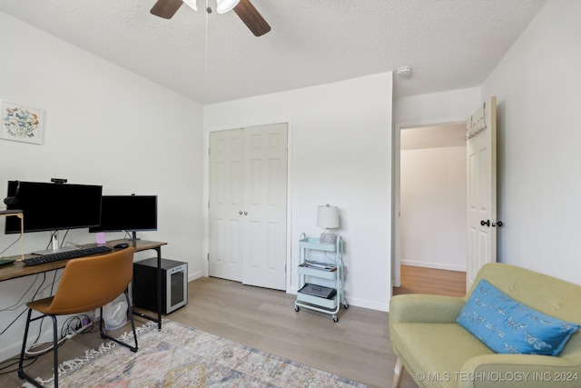 home office featuring light wood-type flooring, ceiling fan, and a textured ceiling