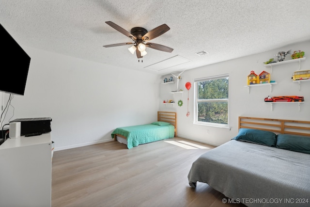 bedroom with ceiling fan, a textured ceiling, and light hardwood / wood-style flooring