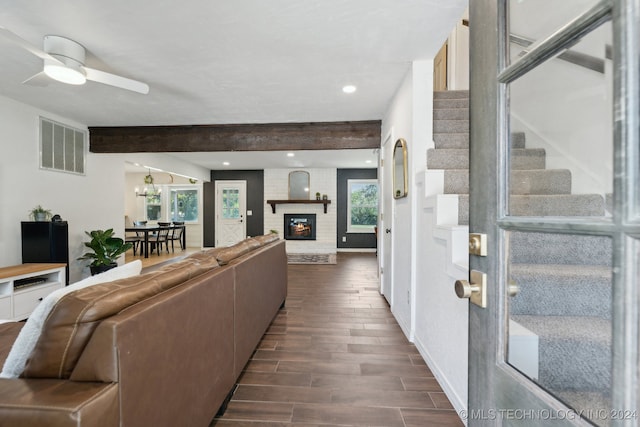 living room featuring a fireplace, ceiling fan, plenty of natural light, and dark wood-type flooring