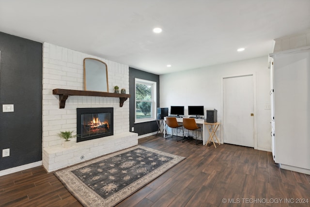 living room featuring brick wall, dark hardwood / wood-style flooring, and a brick fireplace