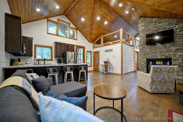 living room featuring wooden walls, a fireplace, light wood-type flooring, and wooden ceiling