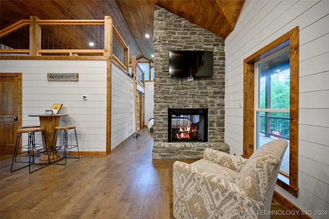 living room featuring hardwood / wood-style floors, a stone fireplace, wooden walls, and wooden ceiling