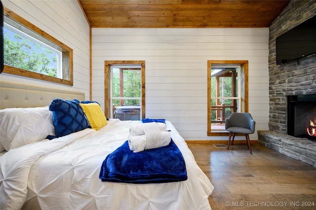 bedroom featuring wood ceiling, a fireplace, and multiple windows