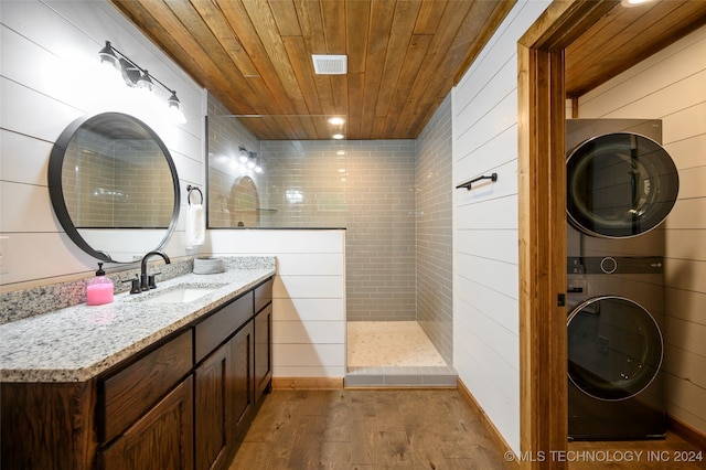 bathroom featuring wood ceiling, vanity, stacked washer / drying machine, a tile shower, and wood-type flooring