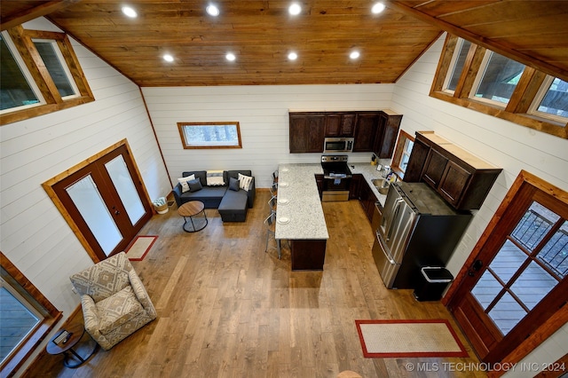 living room featuring lofted ceiling, sink, wooden walls, wooden ceiling, and light wood-type flooring