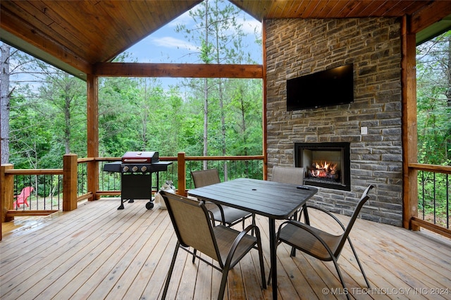 wooden terrace with grilling area and an outdoor stone fireplace