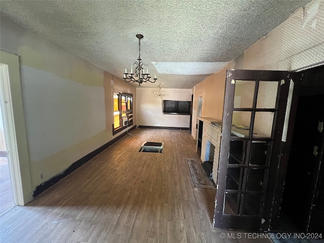 interior space with a textured ceiling, dark hardwood / wood-style flooring, and an inviting chandelier