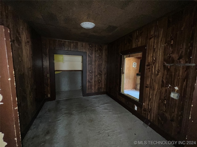 hall featuring wooden walls and concrete floors