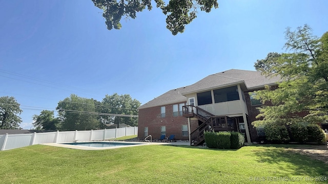 rear view of house with a fenced in pool and a yard