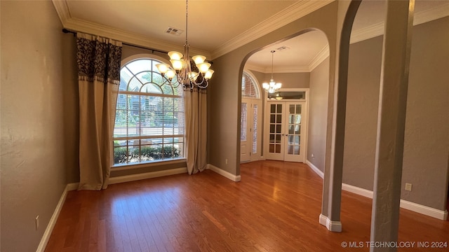 unfurnished dining area featuring french doors, wood-type flooring, ornamental molding, and a chandelier