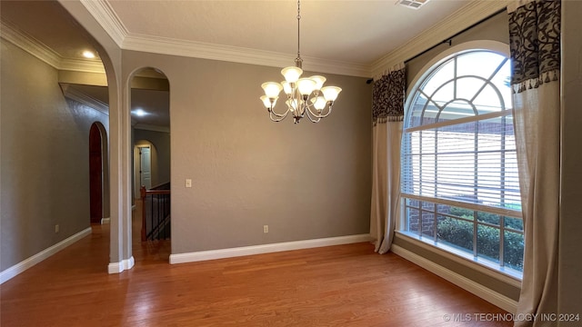 spare room with hardwood / wood-style flooring, an inviting chandelier, and crown molding