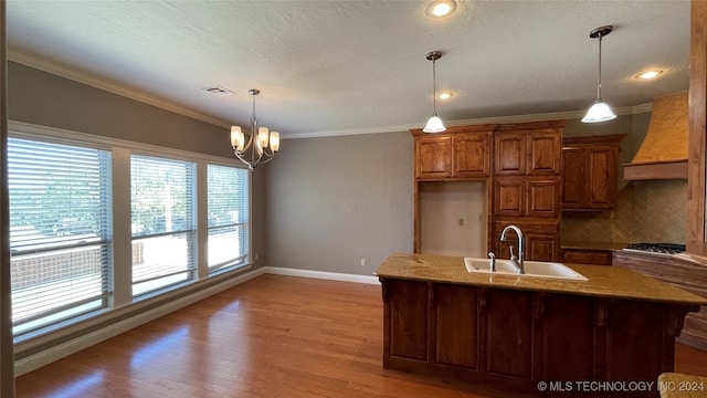 kitchen featuring decorative backsplash, ornamental molding, custom range hood, a chandelier, and hardwood / wood-style floors