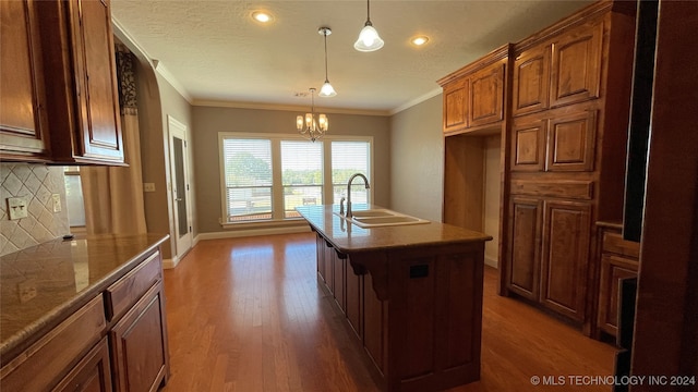 kitchen featuring backsplash, dark wood-type flooring, sink, and hanging light fixtures