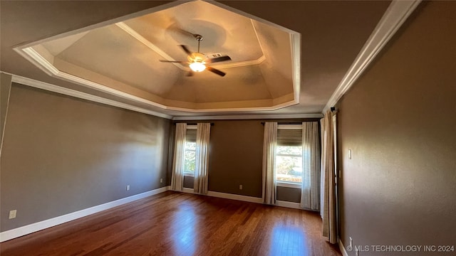 unfurnished room with hardwood / wood-style floors, plenty of natural light, a raised ceiling, and crown molding