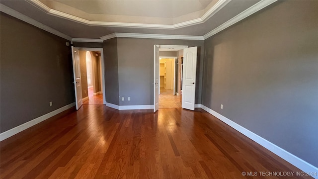 unfurnished bedroom featuring dark hardwood / wood-style flooring, ornamental molding, and a tray ceiling