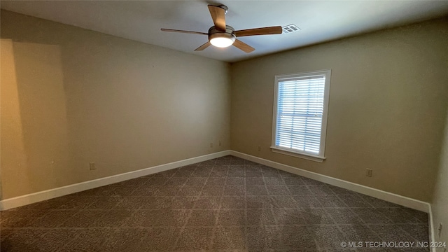 empty room featuring ceiling fan and dark colored carpet