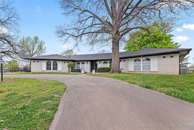 ranch-style house with central air condition unit and a front yard