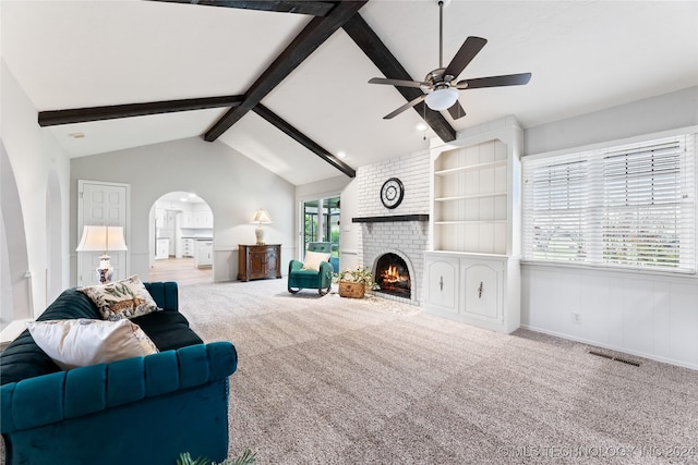 living room with lofted ceiling with beams, a brick fireplace, carpet floors, and ceiling fan