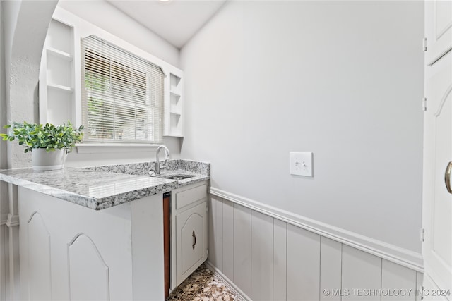 kitchen featuring gray cabinetry, sink, kitchen peninsula, light tile patterned floors, and light stone countertops