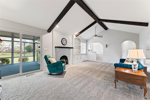 carpeted living room with vaulted ceiling with beams, brick wall, a fireplace, and ceiling fan