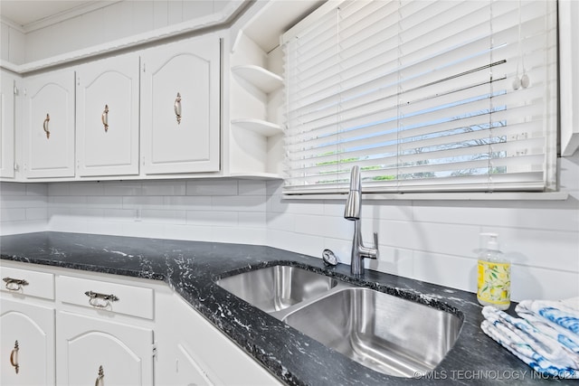 kitchen featuring decorative backsplash, dark stone counters, sink, and white cabinets