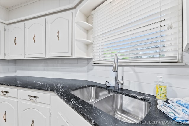 kitchen featuring dark stone countertops, sink, decorative backsplash, and white cabinets