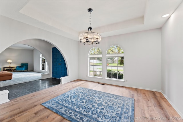 entryway featuring a raised ceiling, dark wood-type flooring, and a chandelier