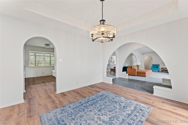 foyer entrance with an inviting chandelier, a tray ceiling, and hardwood / wood-style flooring