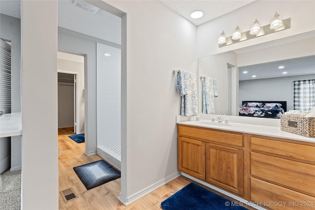 bathroom featuring walk in shower, wood-type flooring, a textured ceiling, and vanity