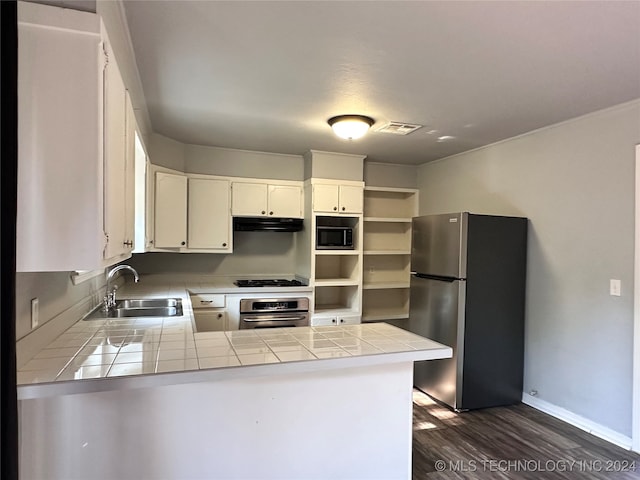 kitchen featuring dark wood-type flooring, tile counters, stainless steel appliances, kitchen peninsula, and white cabinets