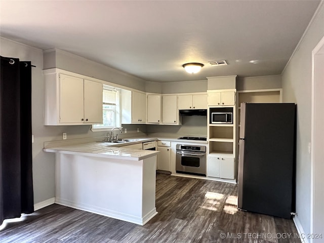 kitchen with appliances with stainless steel finishes, white cabinetry, dark hardwood / wood-style floors, sink, and kitchen peninsula