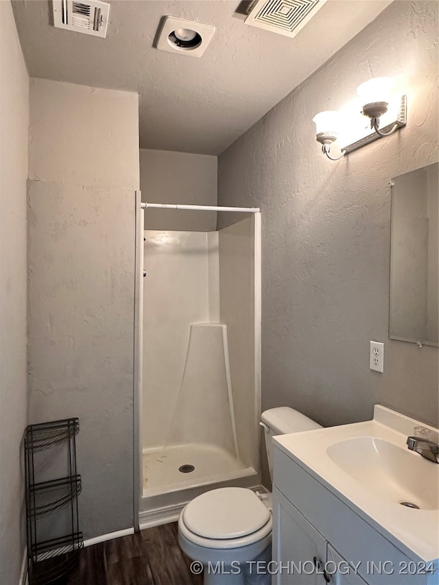 bathroom with hardwood / wood-style flooring, vanity, walk in shower, and toilet