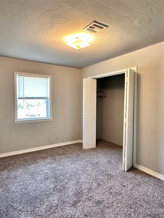 unfurnished bedroom with a textured ceiling and carpet flooring