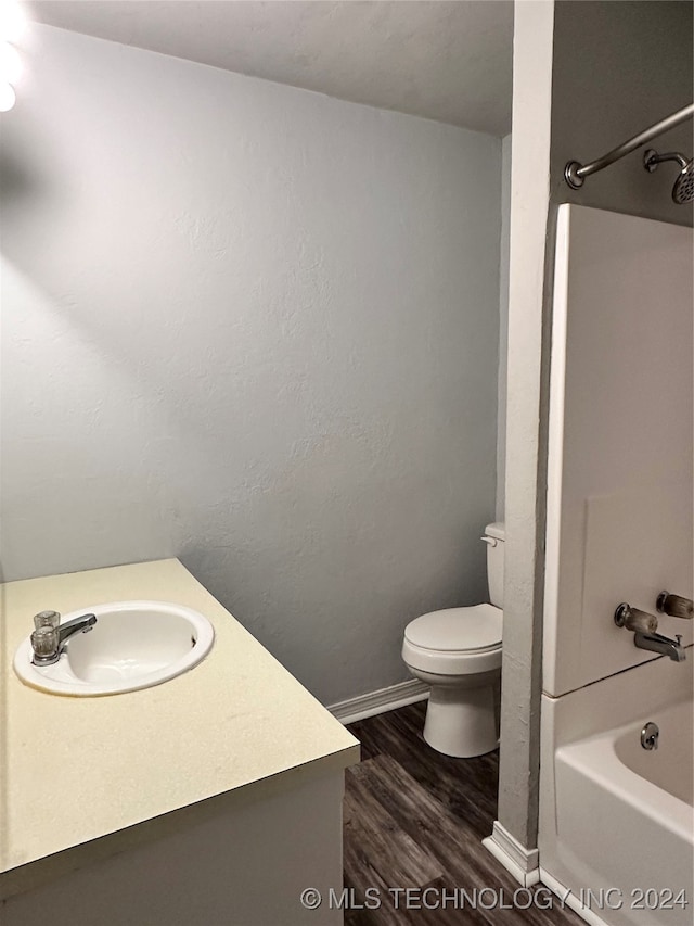 full bathroom with hardwood / wood-style flooring, shower / bath combination, vanity, and toilet