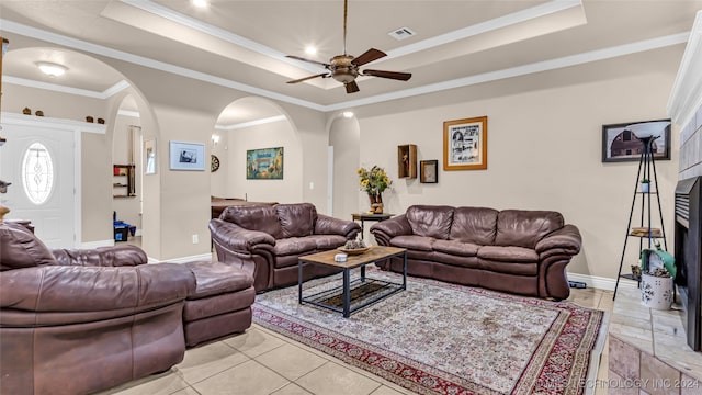 tiled living room with crown molding, a raised ceiling, and ceiling fan