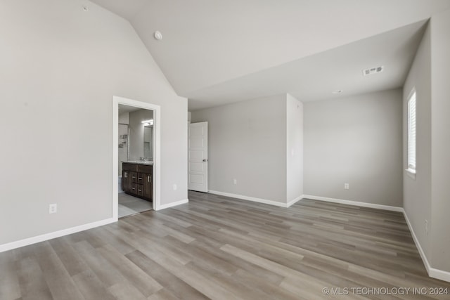 unfurnished bedroom featuring hardwood / wood-style floors, high vaulted ceiling, and connected bathroom