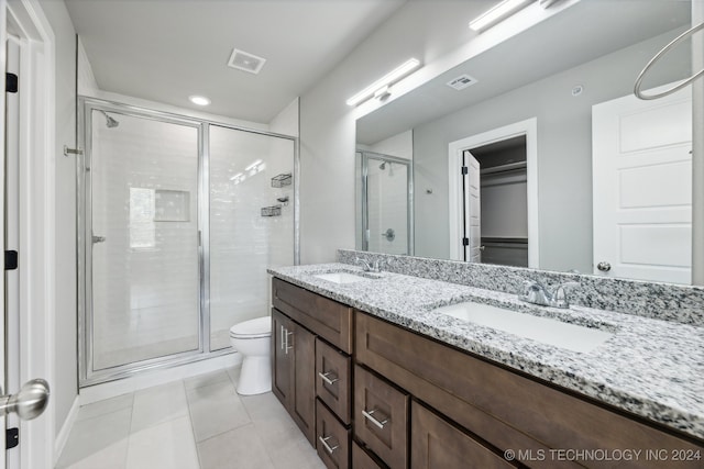 bathroom with toilet, an enclosed shower, dual bowl vanity, and tile patterned flooring