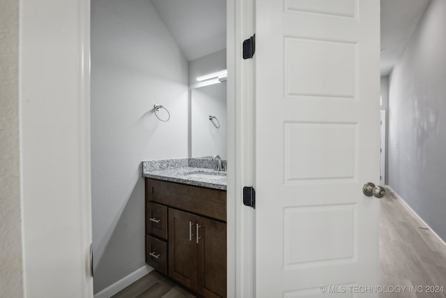 3408 Redbud Ln, Tulsa, OK 74132 - bathroom with vanity, wood finished floors, baseboards, and vaulted ceiling