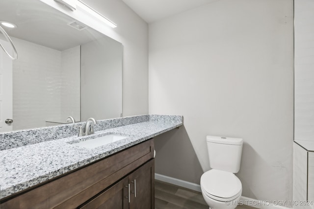 bathroom with toilet, vanity, and hardwood / wood-style floors