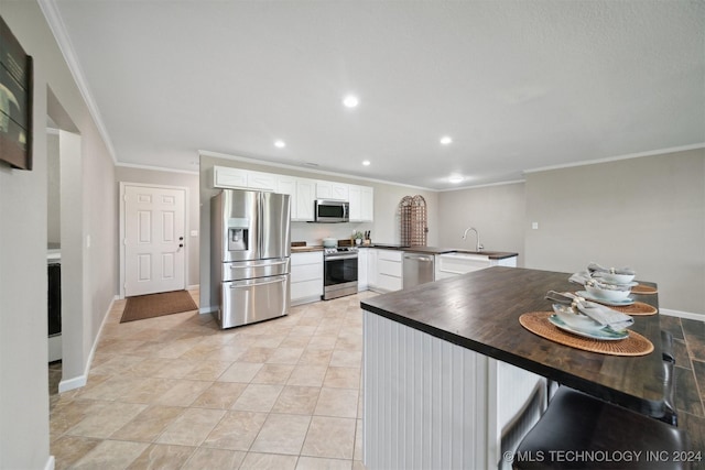 kitchen featuring white cabinets, sink, crown molding, kitchen peninsula, and stainless steel appliances