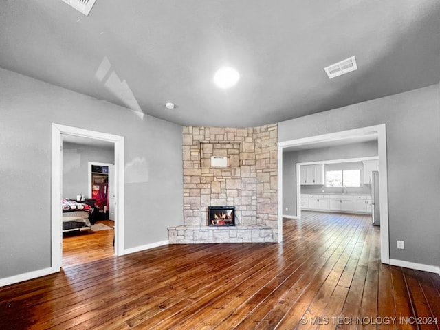 unfurnished living room featuring a stone fireplace and hardwood / wood-style flooring