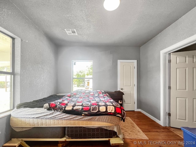 bedroom with hardwood / wood-style flooring and a textured ceiling