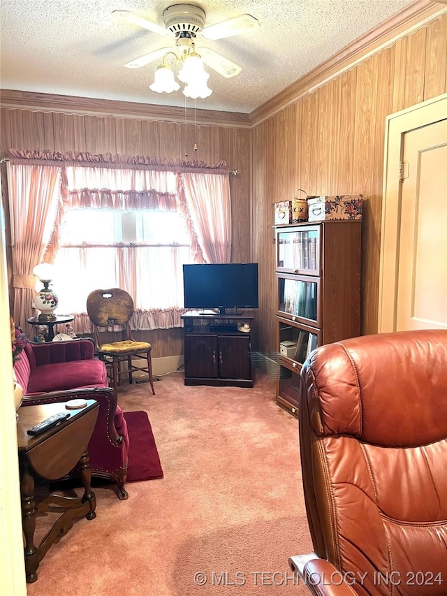 carpeted living room featuring ceiling fan, ornamental molding, wooden walls, and a textured ceiling