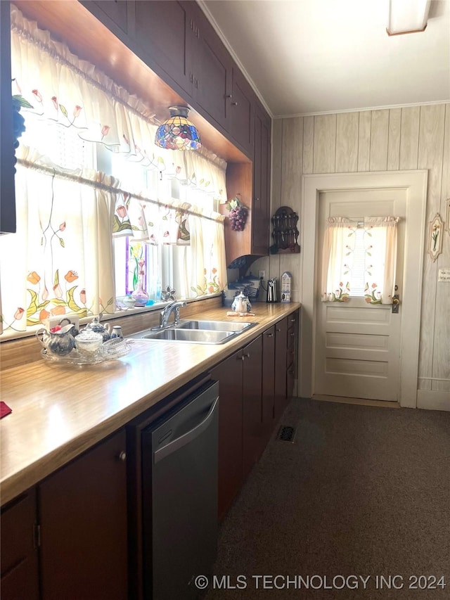 kitchen featuring stainless steel dishwasher, sink, dark brown cabinets, and wooden walls