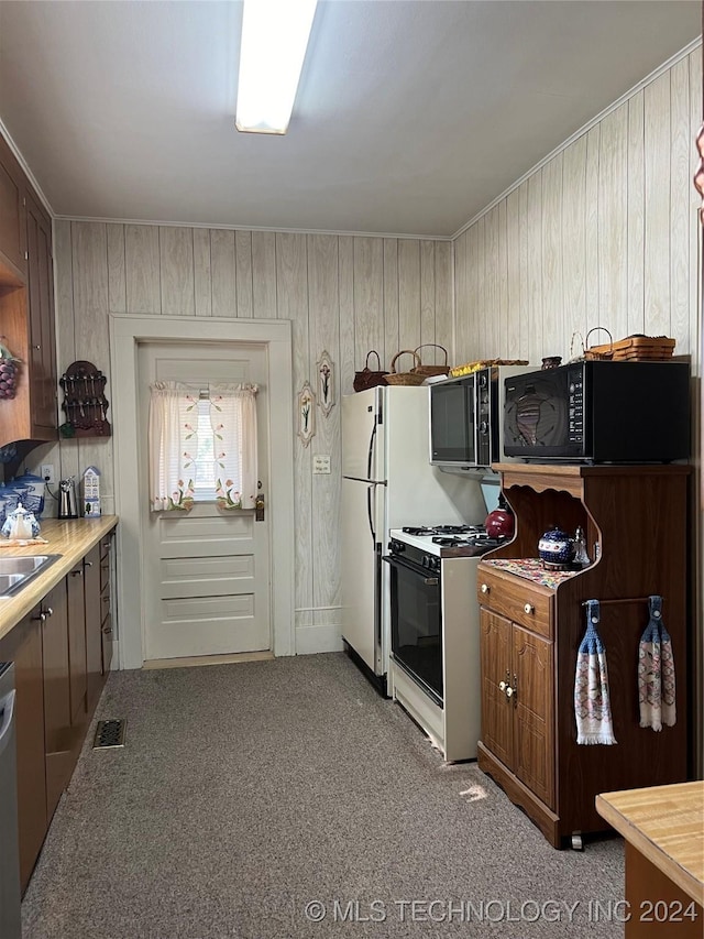 kitchen featuring sink, white appliances, and wooden walls