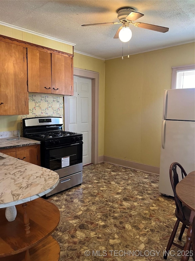 kitchen with gas range oven, white refrigerator, ceiling fan, and a textured ceiling