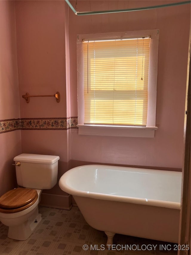 bathroom featuring toilet and a tub to relax in